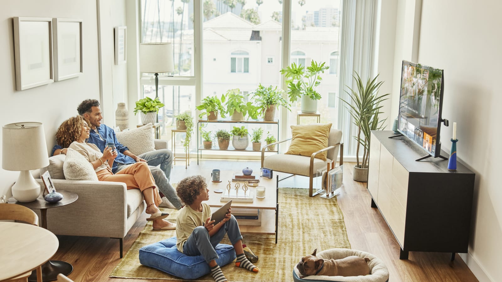 Family relaxing in the living room watching Sling TV on top of entertainment console on their smart, flatscreen TV