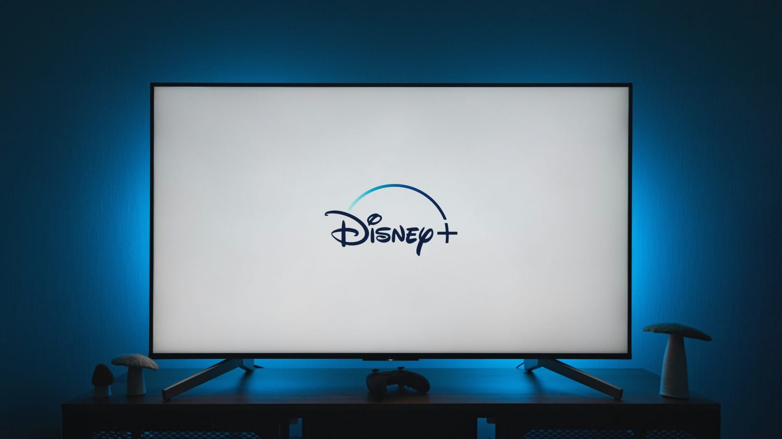 Disney Plus logo displayed on a flat-screen TV with a blue glow