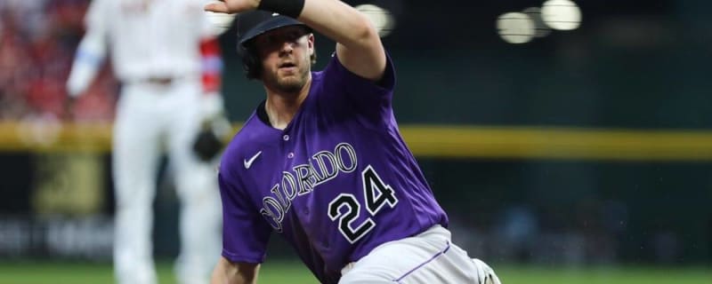 Colorado Rockies' Ryan McMahon, left, gestures to the dugout after hitting  a triple to drive in two runs as Cincinnati Reds third baseman Mike  Moustakas looks on in the sixth inning of