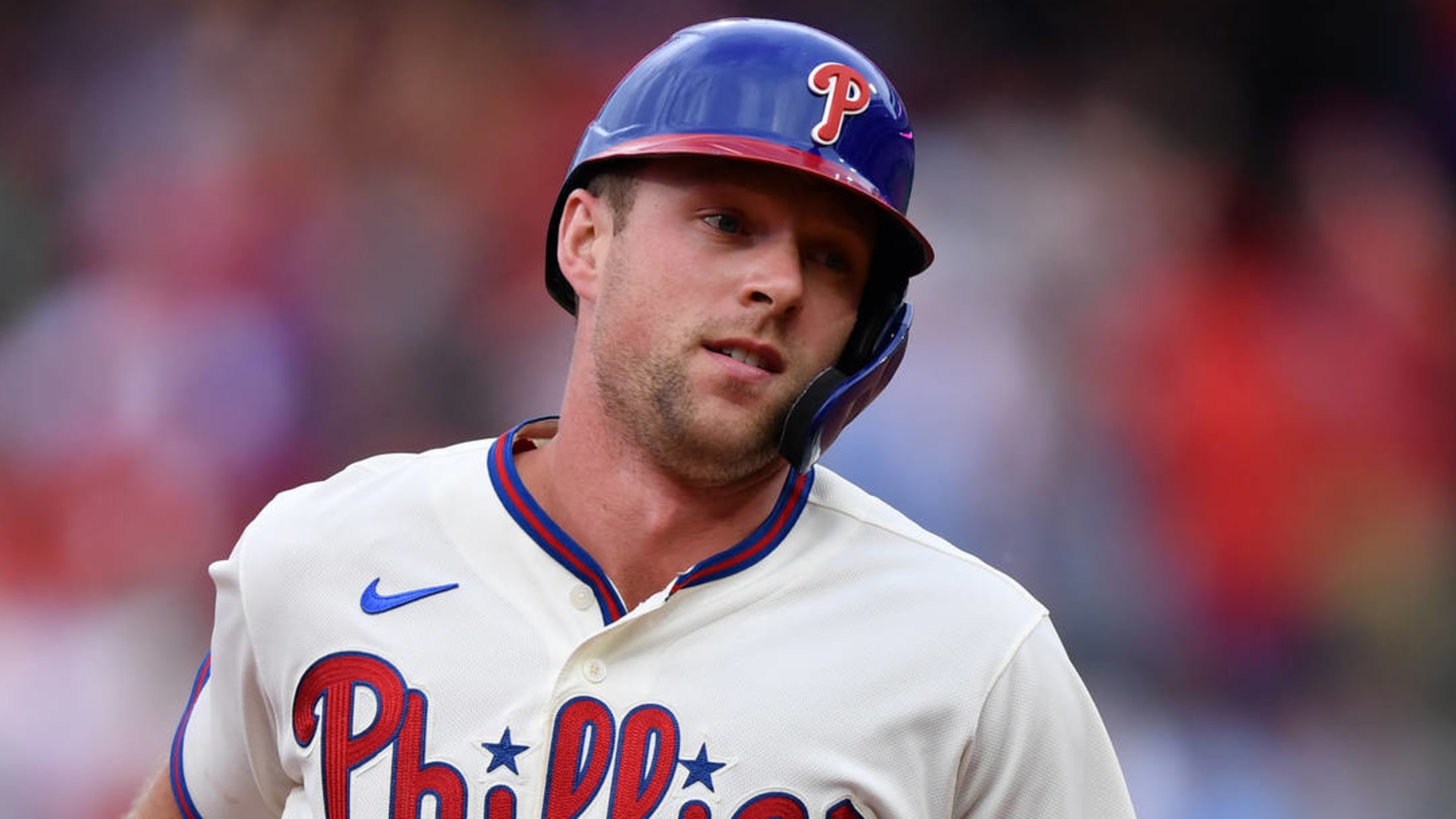 Philadelphia Phillies - Rhys Hoskins, wearing the cream Phillies uniform,  celebrating with the dugout after scoring a run.