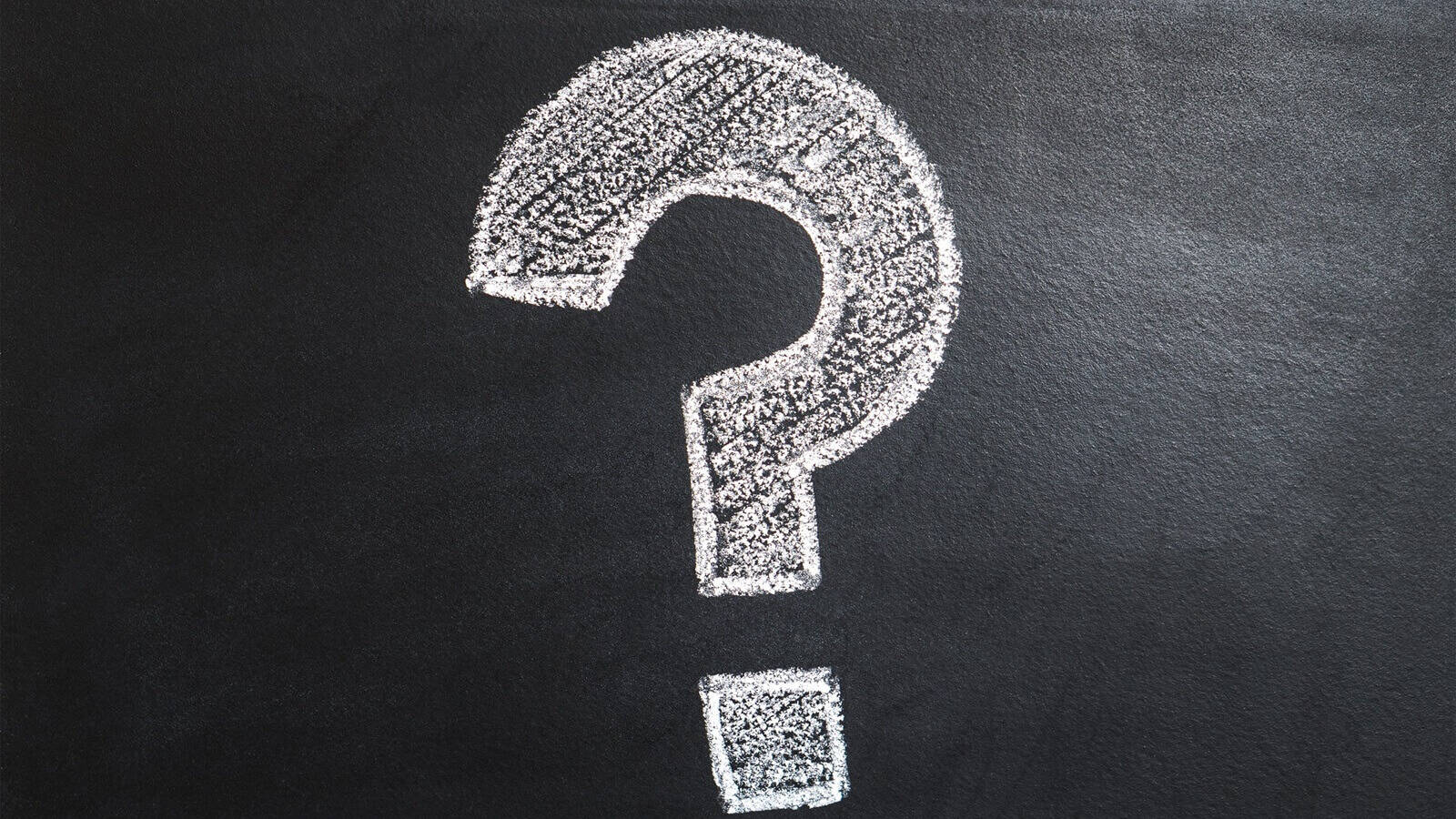White chalk question mark on a black background.