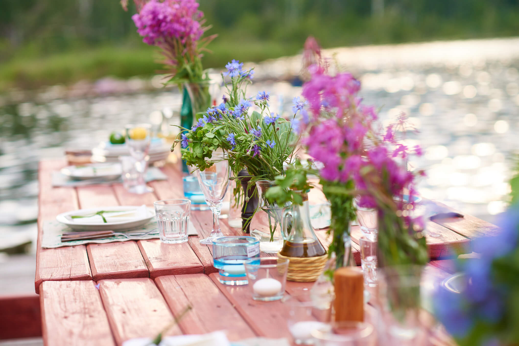 An outdoor patio table with flowers in vases at a Hamptons vacation home