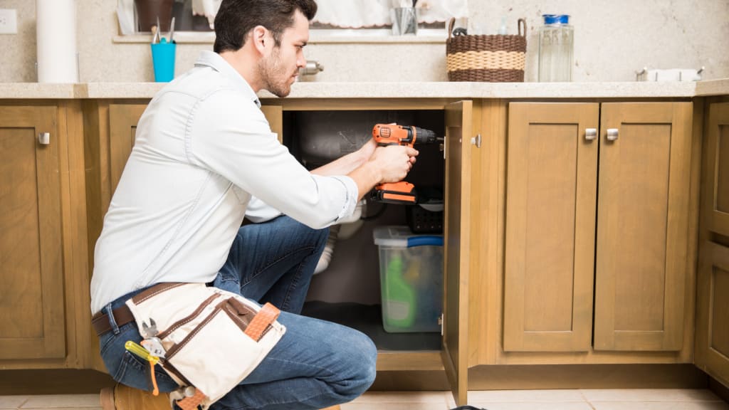 A handyman drilling into a cabinet - a common service on a handyman services list