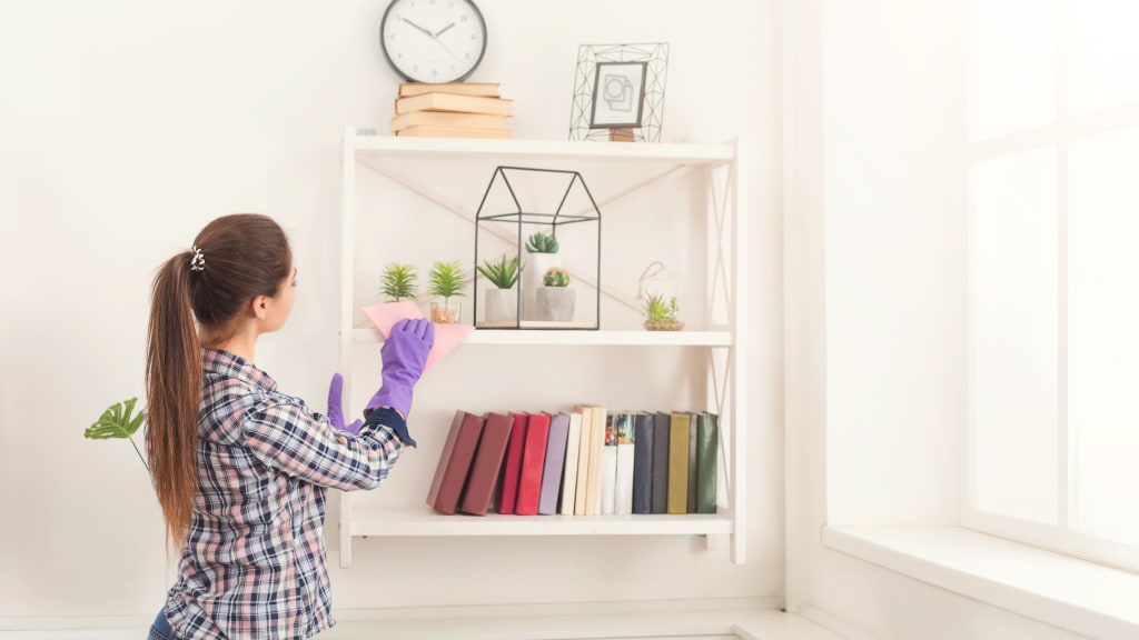 A woman dusts, tackling her Spring Cleaning List Room by Room