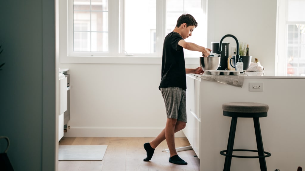 A boy works in a kitchen, one of many age appropriate chores for kids to do