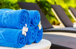 Blue towels are rolled up and placed on a poolside table