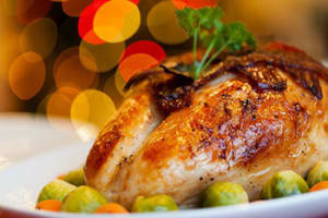 Roast chicken sits on a white plate with vegetables