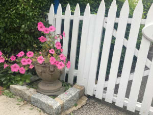 Flowers stand in a pot next to a front gate, a welcome set up as part of Hamptons vacation rental turnover cleaning services