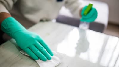 A gloved hand hand wiping down a counter as part of deep house cleaning services