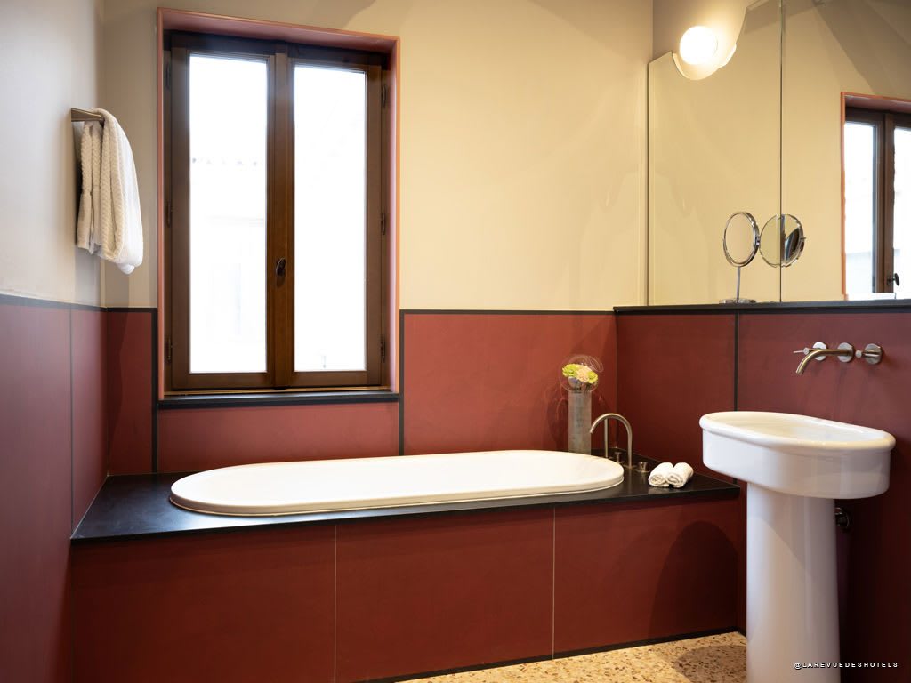 Salle de bains d’une chambre de l’Elizabeth Unique Venice, baignoire îlot et carrelage terracotta