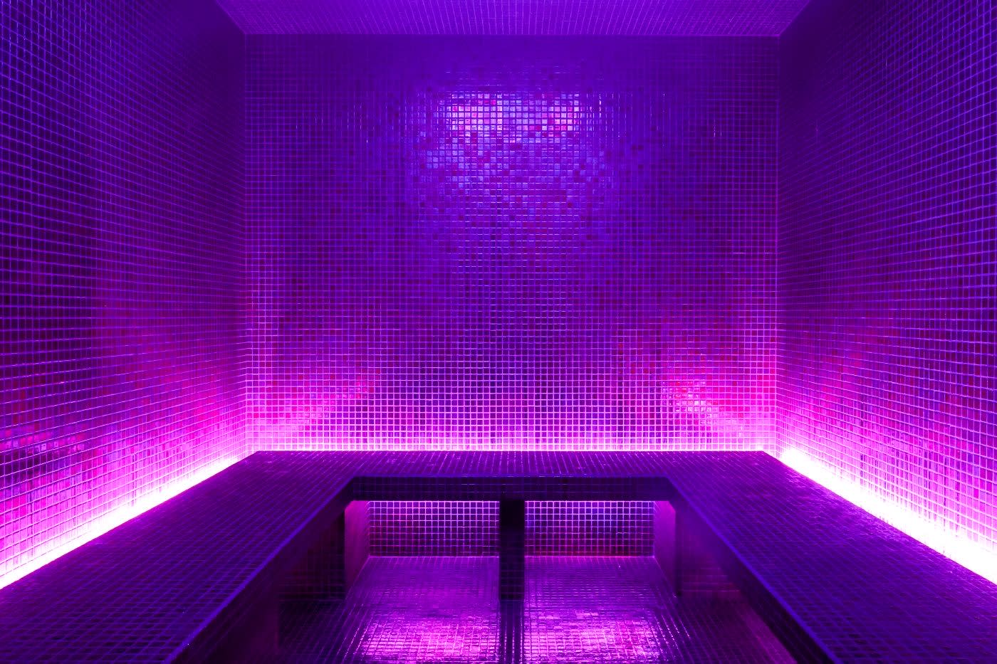 The hammam of the FORêT spa at Chalet Frère Joseph, lined with mosaic under violet light