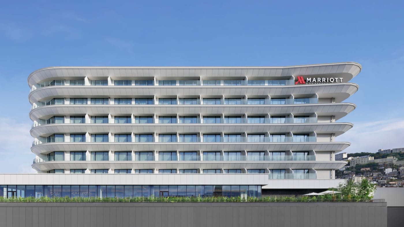 The white facade with curved balconies of the Nagasaki Marriott Hotel, above Nagasaki station