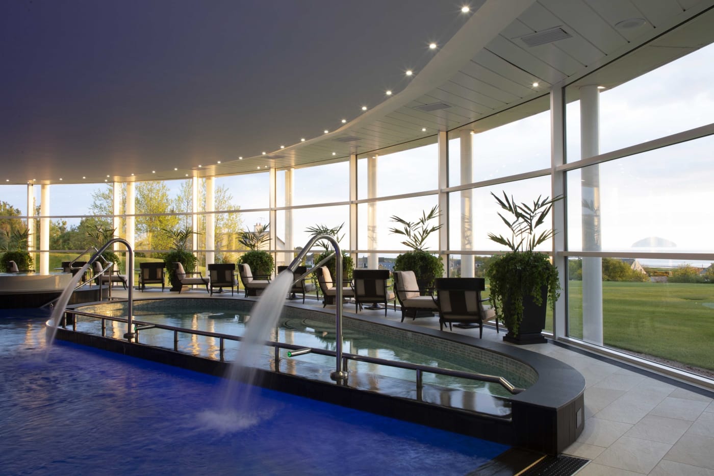 La piscine intérieure du spa de Trump Turnberry, ses jets d'eau et son bain chaud sous une verrière ouverte sur les pelouses