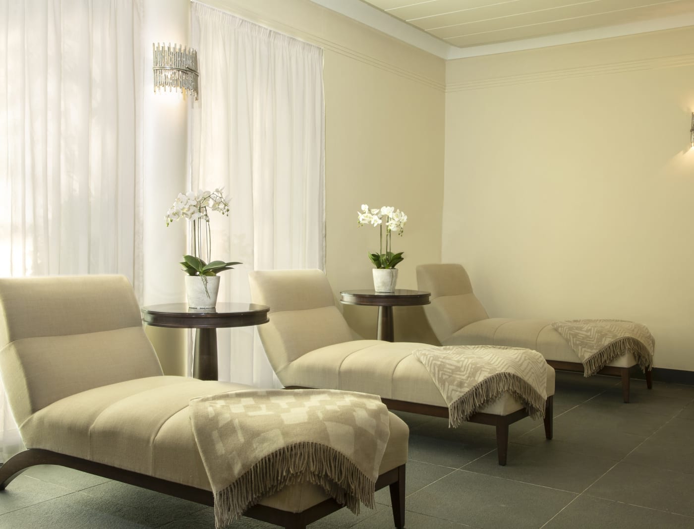 La salle de relaxation du spa de Trump Turnberry, avec ses méridiennes crème, ses plaids et ses orchidées