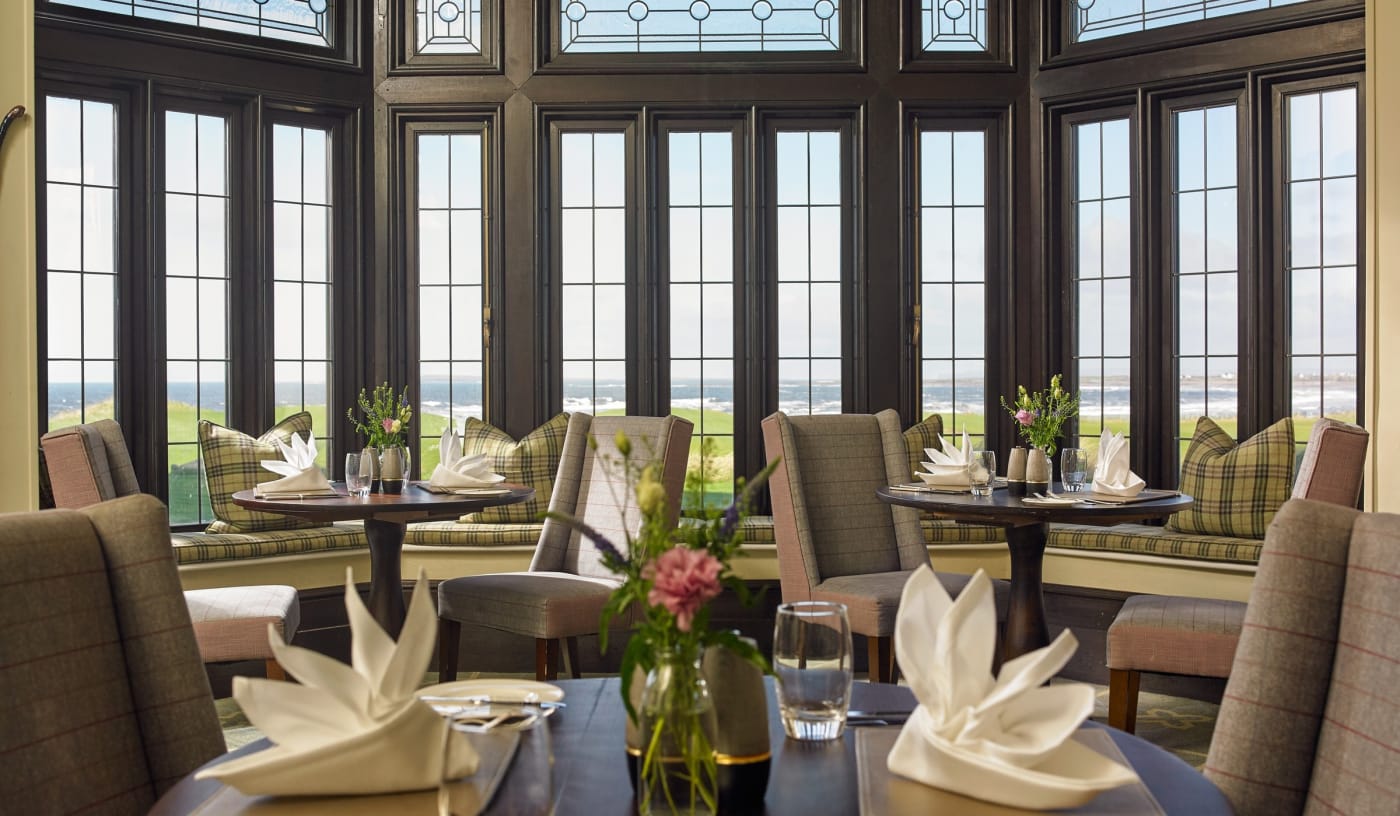 Les tables dressées de l'Ocean View Restaurant du Trump International Doonbeg, devant un bow-window ouvert sur les links et l'Atlantique