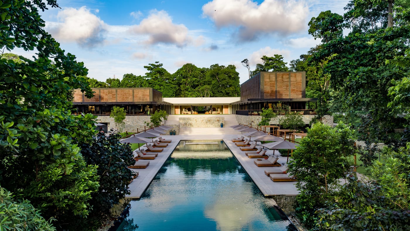 The large pool at the Mandarin Oriental, Desaru Coast, lined with loungers in the heart of the tropical forest