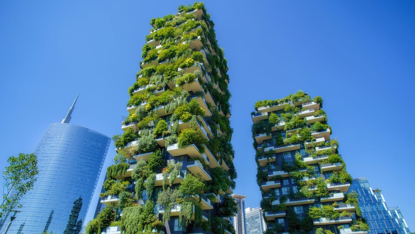 Die beiden begrünten Türme des Bosco Verticale und ein Glasturm im Viertel Porta Nuova in Mailand unter blauem Himmel