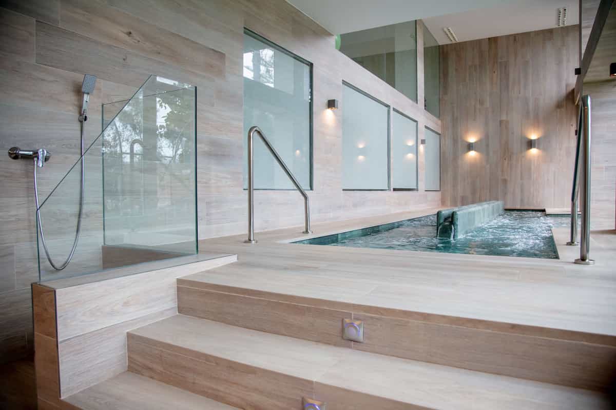 Piscina de hidroterapia con paredes de madera clara en la clínica Palasiet