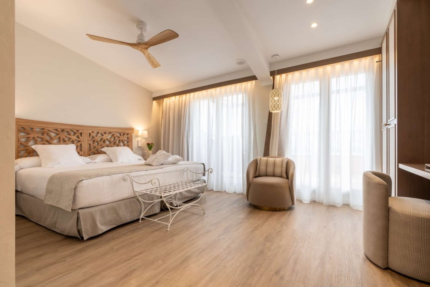 Habitación de Palasiet en tonos arena, con parquet claro y visillos