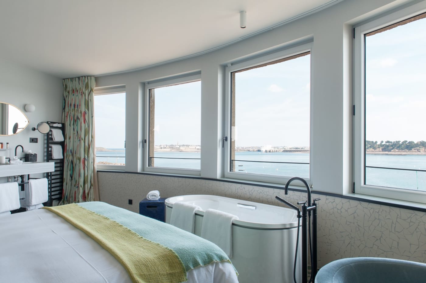 Ein Zimmer im Hotel Castelbrac mit freistehender Badewanne und Fenstern zur Bucht von Saint-Malo