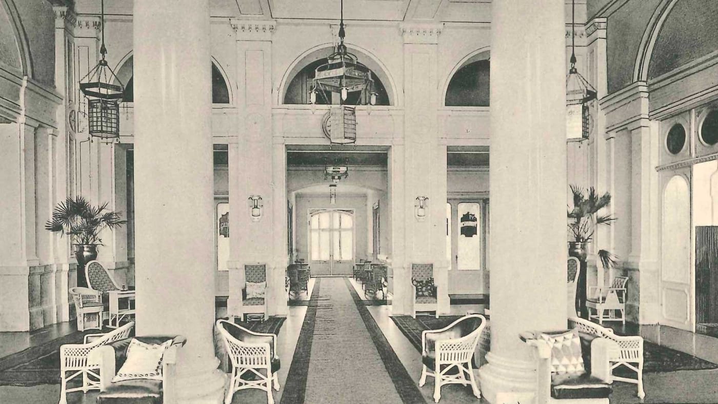 Historische Aufnahme der Säulenhalle des Palace Merano mit ihren Rattansesseln