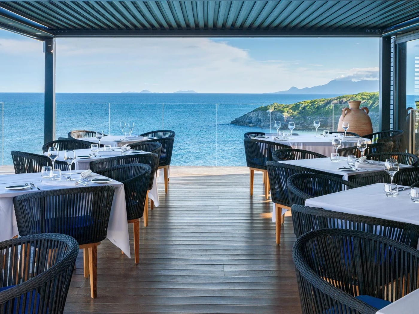 Eingedeckte Tische im Restaurant Le Grand Bleu des La Toubana, offen zum Meer und zu den fernen Inseln