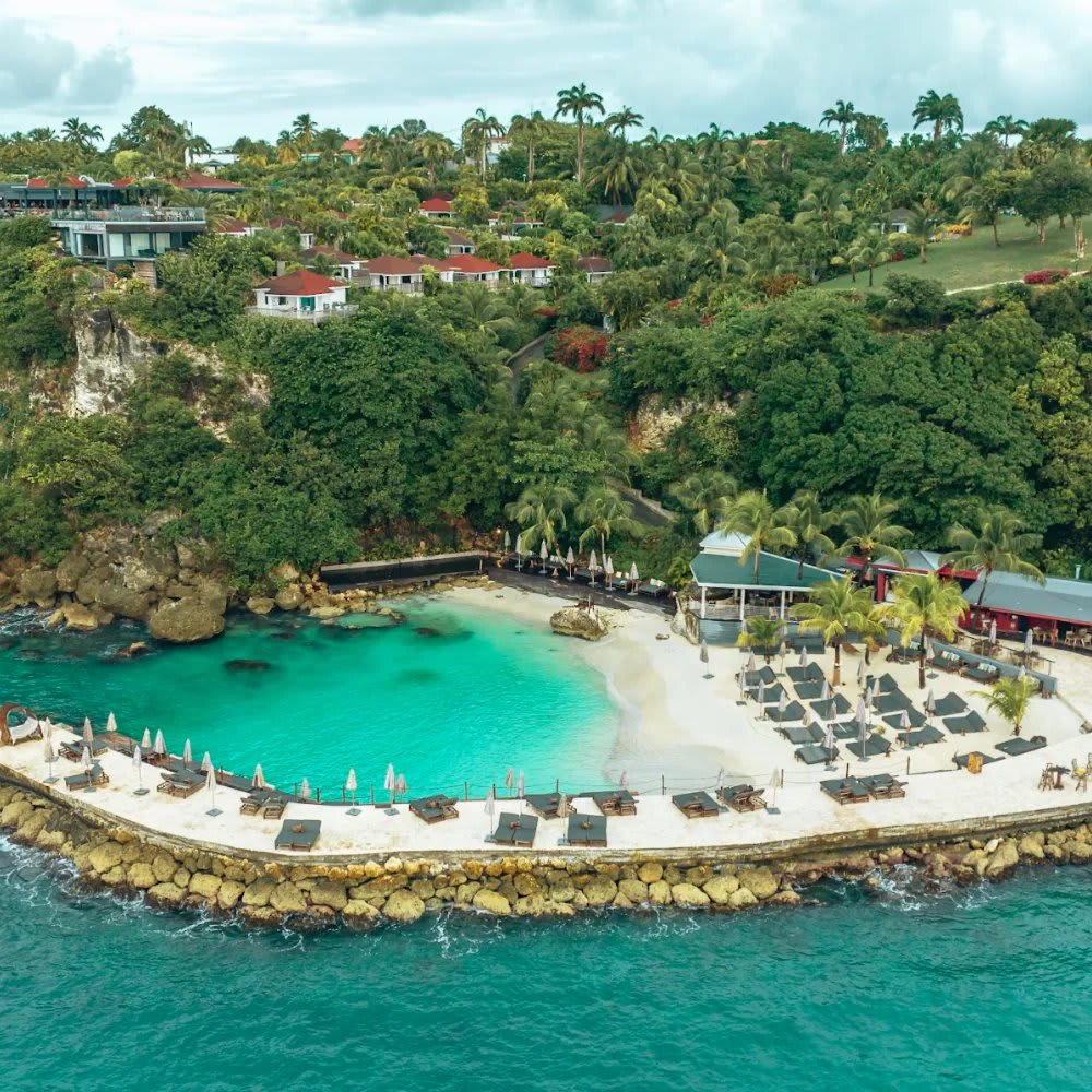 Luftaufnahme des hoteleigenen Strands des La Toubana Hôtel & Spa mit Mole und Liegestühlen am Fuß der Klippe