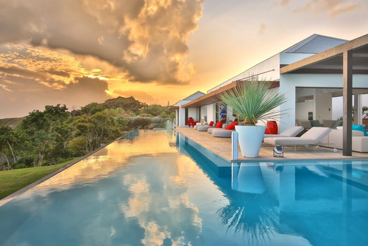 Eine Villa des La Toubana Hôtel & Spa mit langem Infinity-Pool bei Sonnenuntergang