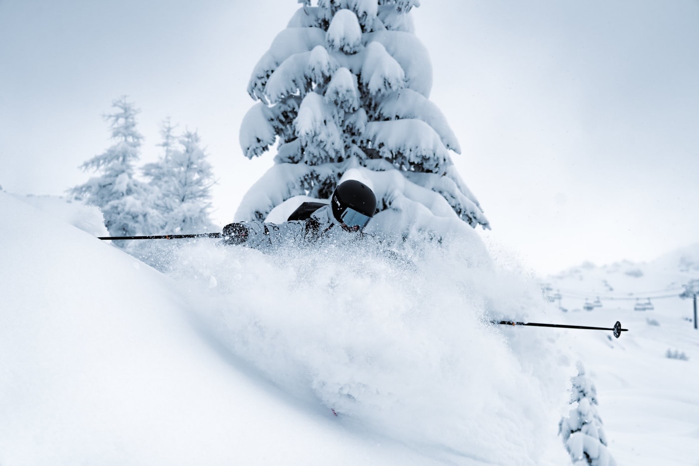 Ein Skifahrer wirbelt unter einer verschneiten Tanne in Sainte-Foy-Tarentaise Pulverschnee auf