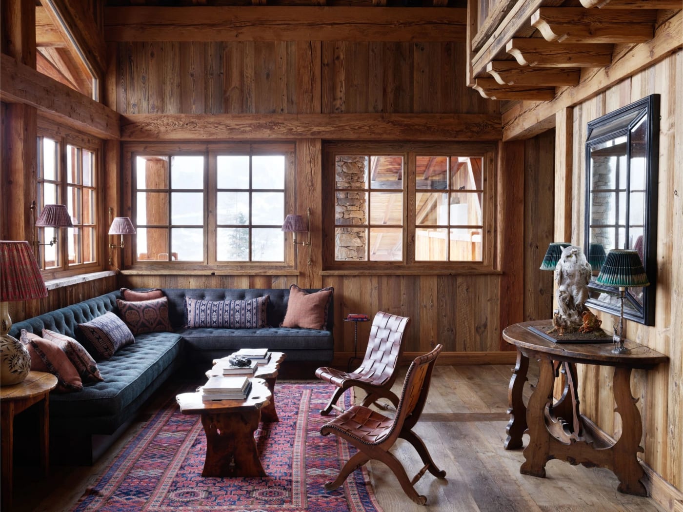 Der holzgetäfelte Salon des Chalet Hibou von Eleven mit alten Teppichen und Sitzbank, in Le Miroir