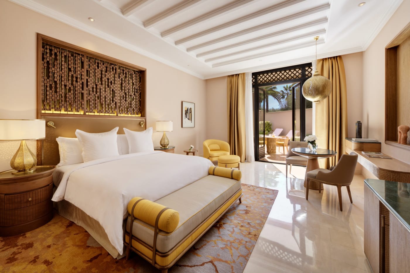 Chambre du Four Seasons Resort Marrakech, lit blanc, plafond à poutres et porte-fenêtre ouverte sur une terrasse