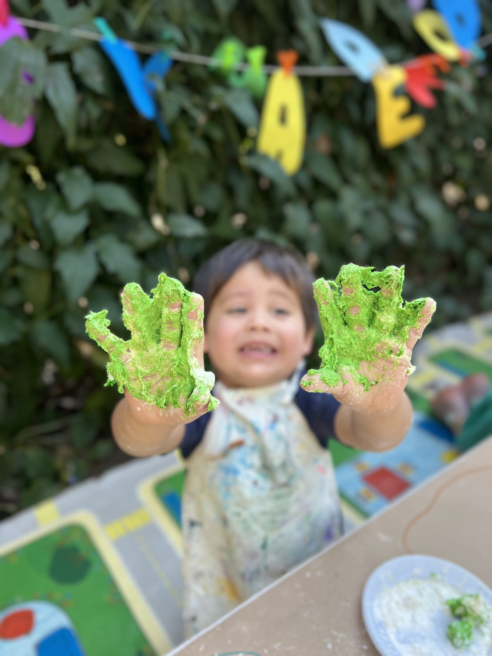 Mãos de criança com tinta verde na atividade pedagógica da Da Vinci Academy