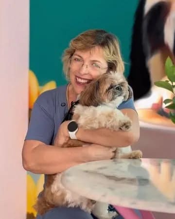 Integrante da equipe da Hospedogs segurando um cão de pequeno porte no colo