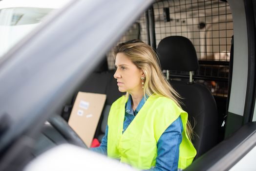 conducteur en gilet haute visibilité badge une clé RFID sur le tableau de bord d'un utilitaire, matin gris, dépôt logistique en arrière-plan