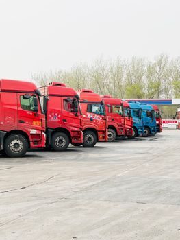 Un gestionnaire de flotte dans un bureau de dépôt de transport routier, consultant un écran affichant une carte avec plusieurs camions géolocalisés, ambiance professionnelle, lumière naturelle du matin, entrepôt visible en arrière-plan