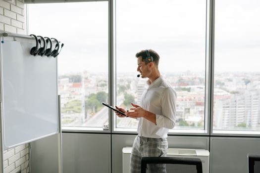 Un gestionnaire de flotte consultant un tableau de bord de dépenses sur tablette dans un bureau de dépôt logistique, lumière naturelle, ambiance professionnelle et concentrée