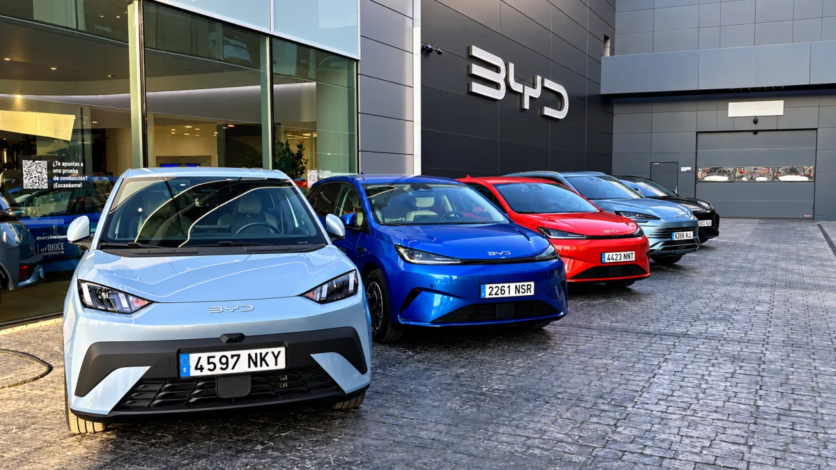 Fila de automóviles BYD de diferentes colores aparcados en el exterior de un concesionario con el logotipo de la marca en la fachada.