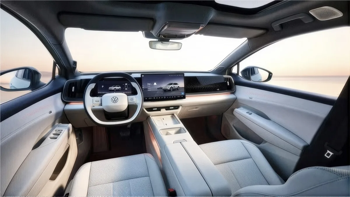 Vista frontal del interior de un automóvil con tapicería clara, volante con el logotipo de Volkswagen y pantallas digitales en el salpicadero.