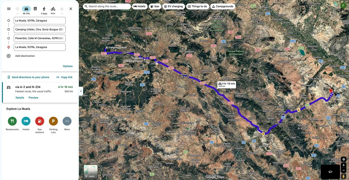 Captura de pantalla de Google Maps en vista satelital que muestra una ruta trazada en azul entre La Muela, Zaragoza, y el Camping Urbión pasando por un punto de recarga.