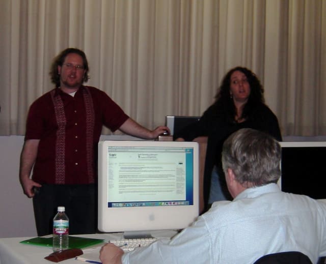 Me and Molly presenting at TechEd in 2005. We’re at the front of a darkened conference room and someone in front of us is looking at the World Organization of Webmasters’ website on a CRT monitor.