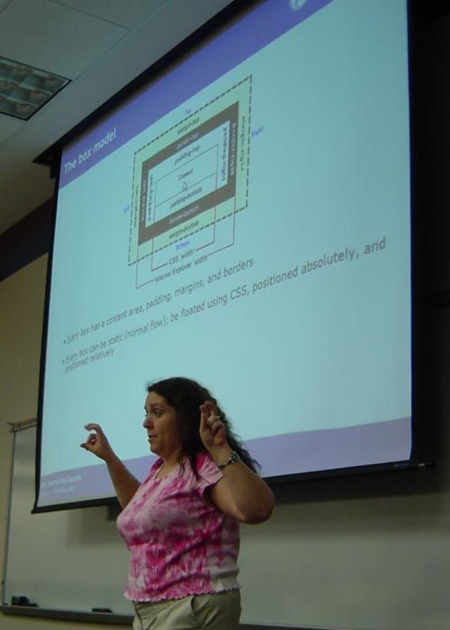 In this photo Molly is teaching people about the CSS box model. The screen behind her shows a dissection of the different parts that affect an element’s dimensions and layout.