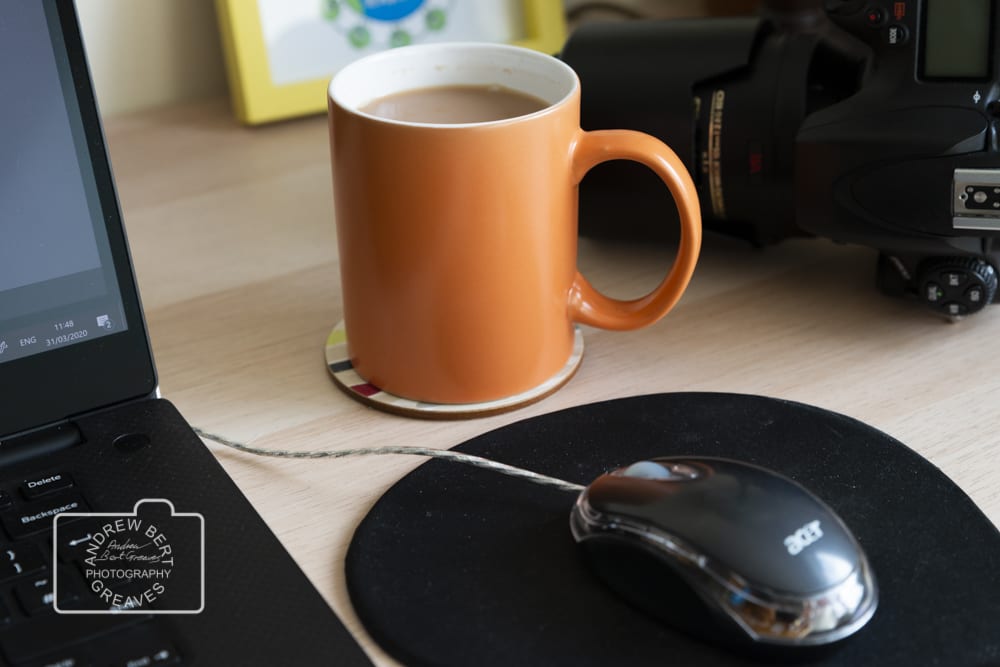 A mug of tea, laptop and a DSLR camera