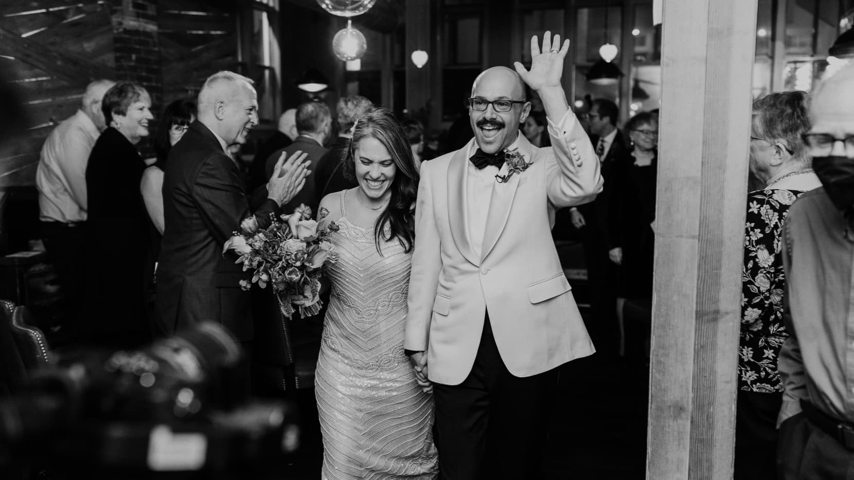 Andrew & Meredith walking back up the aisle after getting marries triumphantly, hand in hand, with arms raised