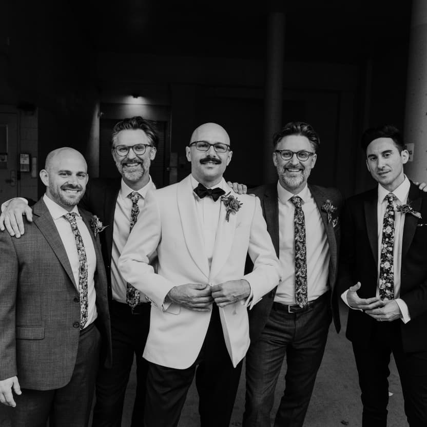 Andrew and some of the groomsmen standing in a serious, stately pose in a dark garage alley
