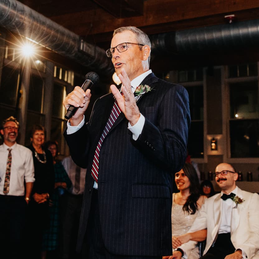 Ben giving his father-of-the-bride toast with a mic in his hand