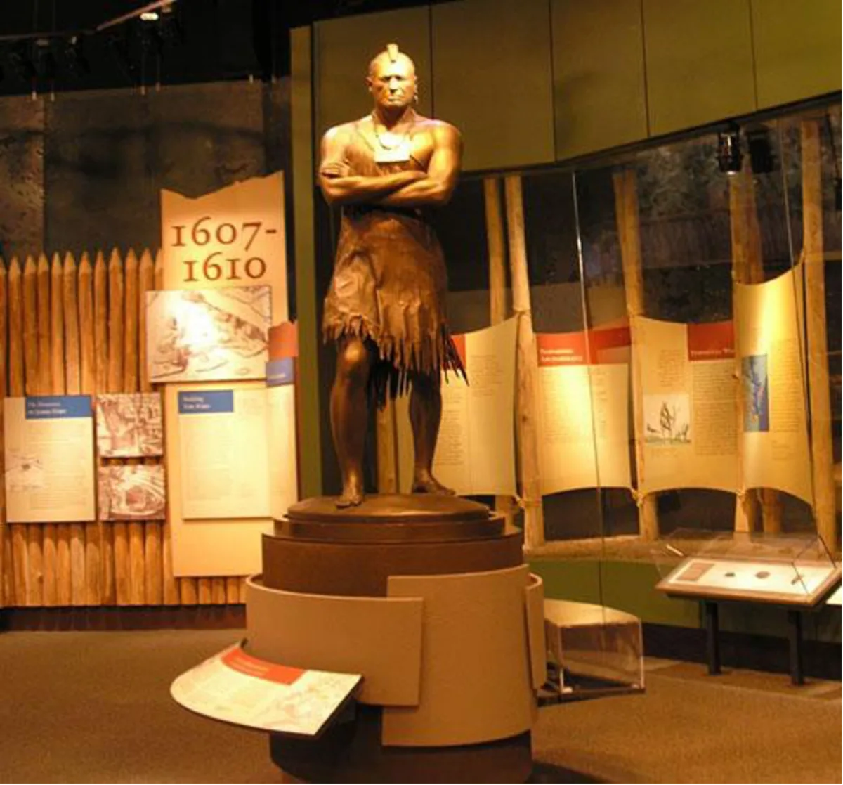 bronze statue of native american chief standing defiantly, in center of museum room