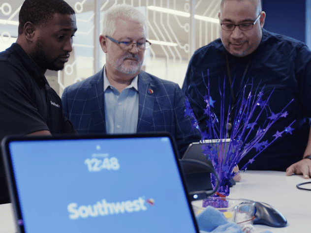 Tre dipendenti di Southwest Airlines esaminano i dati su più schermi