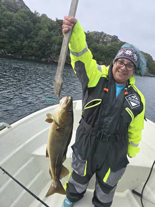 Smiling guest holding up a freshly caught cod