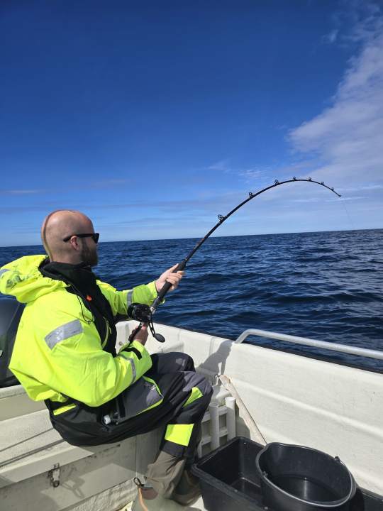 Guest fishing from the boat with the rod bent by a fish