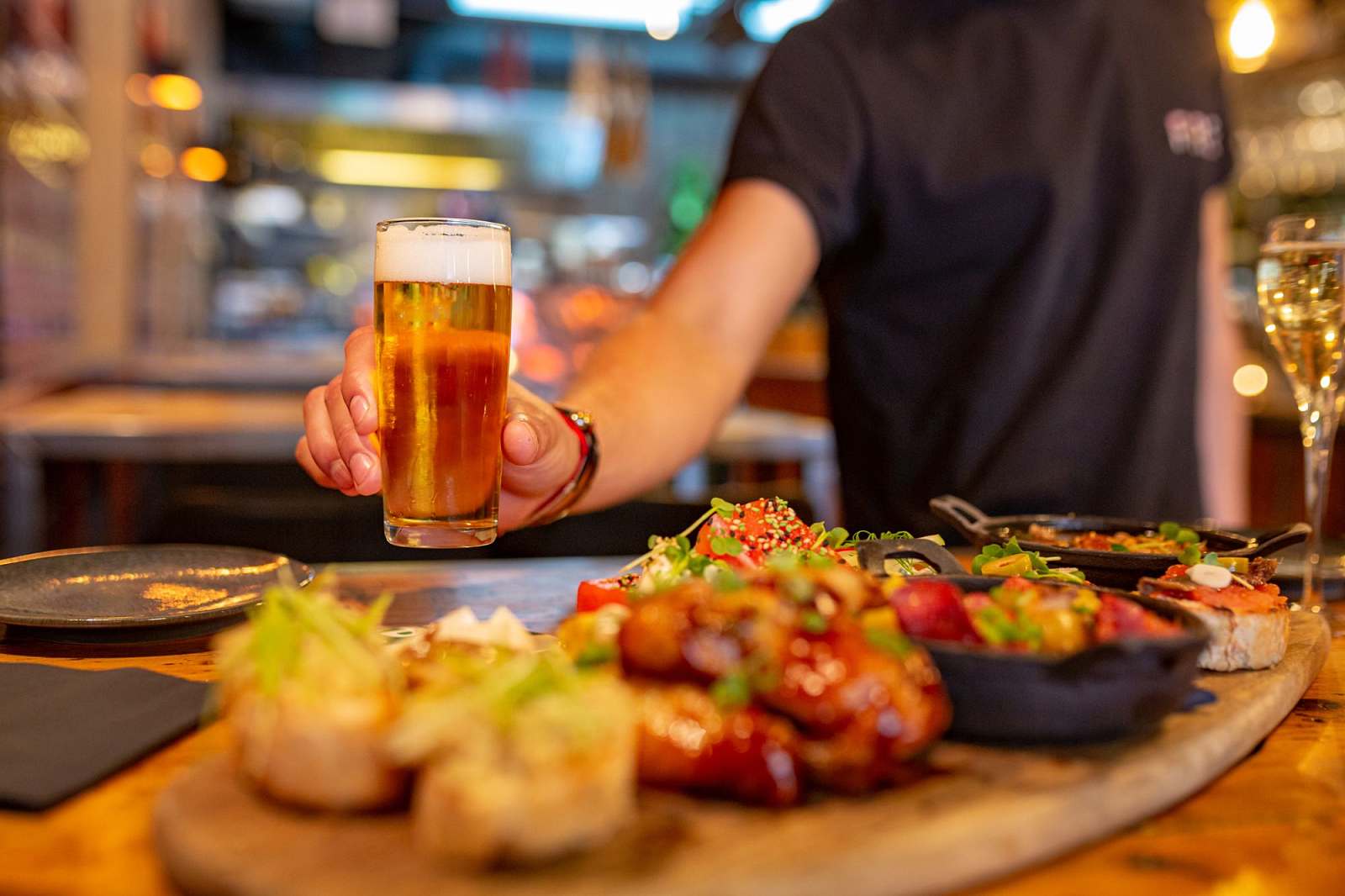 Waiter serving beer at a Spanish restaurant with a table full of tapas